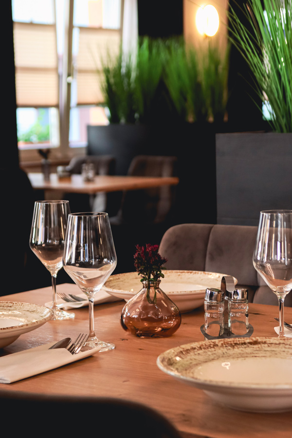 Gedeckter Tisch mit Weingläsern, Pasta-Tellern und Blumenvase
